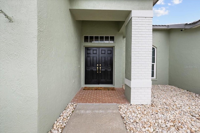 view of exterior entry featuring stucco siding and brick siding