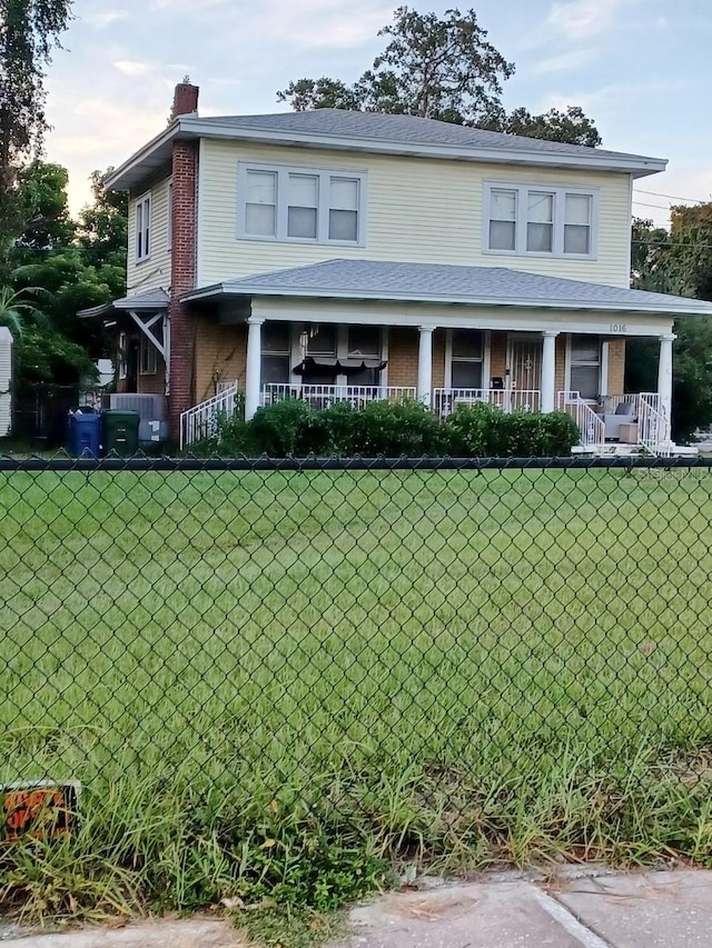 view of front facade featuring a porch, a chimney, and a front lawn