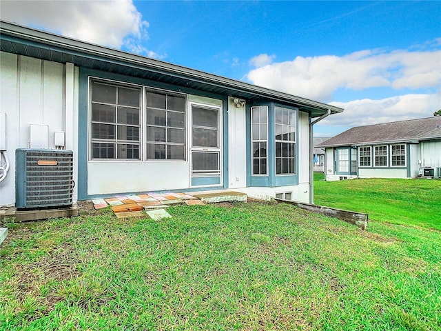 back of property featuring central AC unit and a lawn