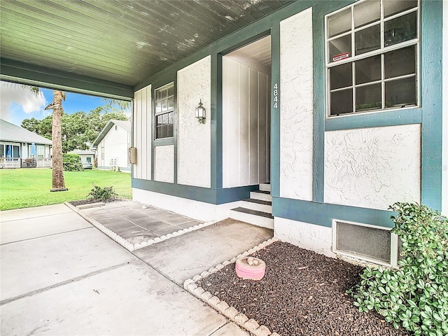 entrance to property featuring a yard and stucco siding