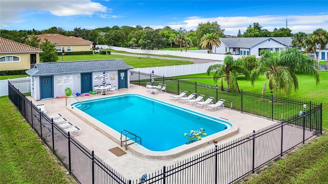 community pool with a patio, a yard, and fence