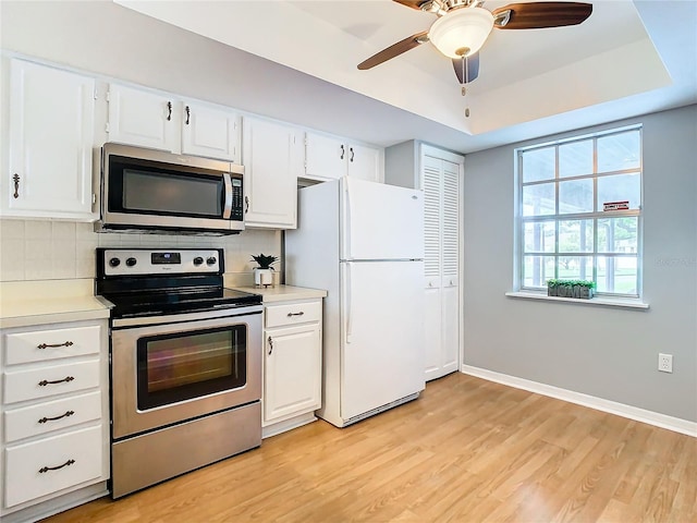 kitchen featuring appliances with stainless steel finishes, light hardwood / wood-style flooring, decorative backsplash, white cabinets, and ceiling fan