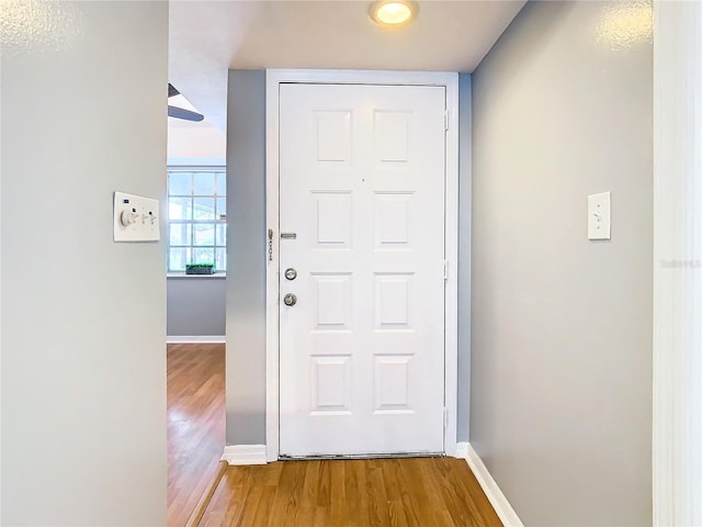 doorway featuring baseboards and wood finished floors