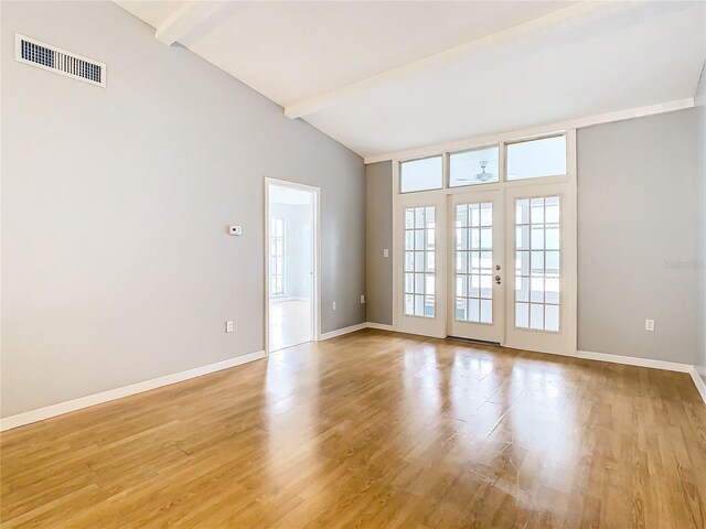 empty room featuring high vaulted ceiling, light hardwood / wood-style floors, beamed ceiling, and french doors