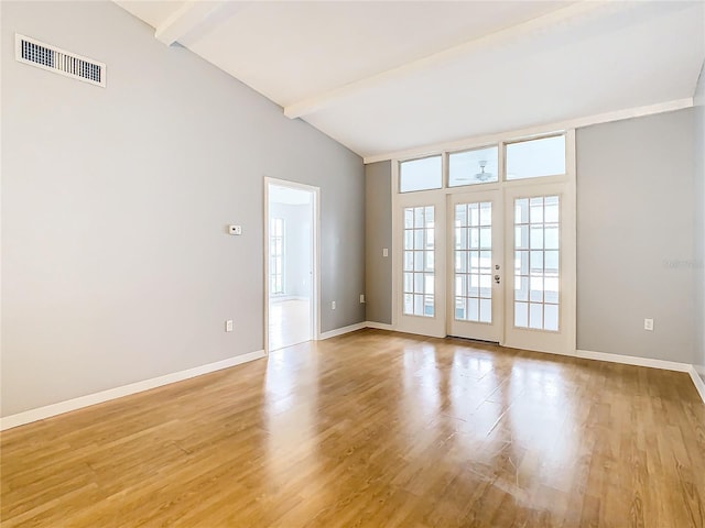 spare room featuring light wood-style floors, vaulted ceiling with beams, french doors, and visible vents