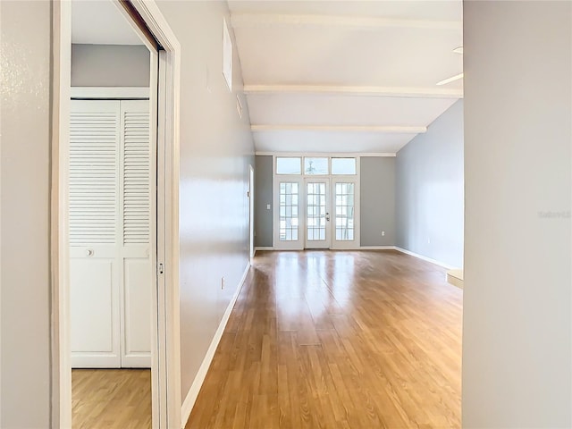 empty room featuring wood finished floors, beamed ceiling, french doors, and baseboards