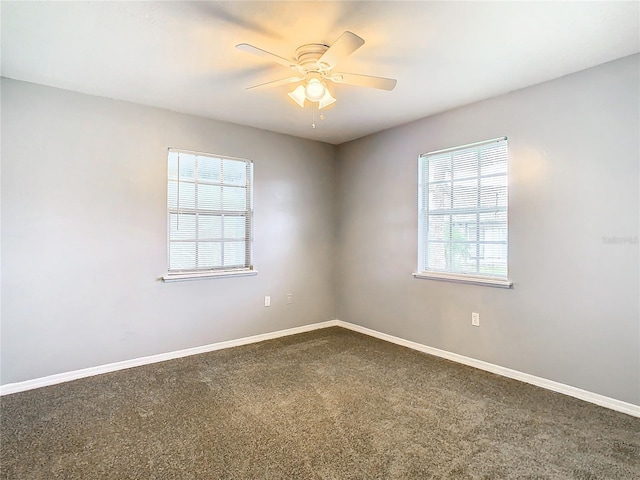 spare room with dark carpet, baseboards, and a ceiling fan