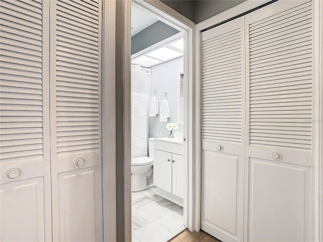 bathroom featuring a closet, marble finish floor, and toilet