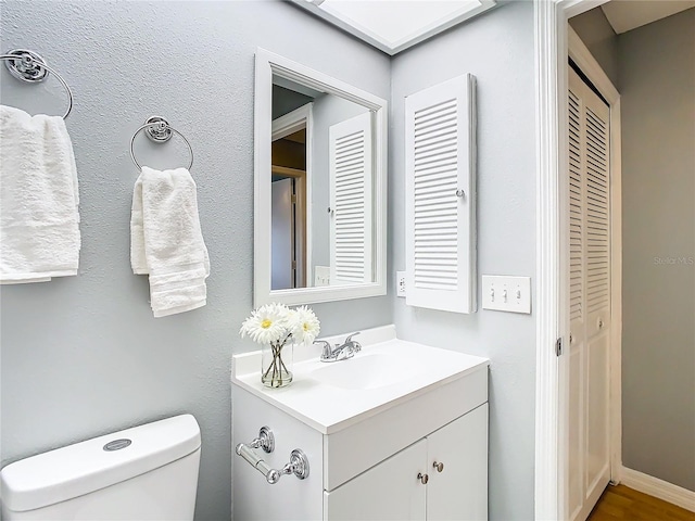 half bath with vanity, toilet, and baseboards