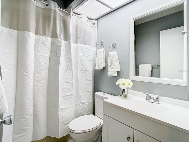 bathroom with curtained shower, vanity, and toilet