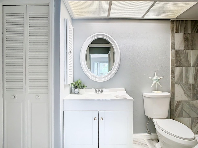 bathroom with a closet, toilet, and vanity