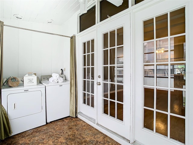 clothes washing area with laundry area, washing machine and dryer, and stone finish flooring