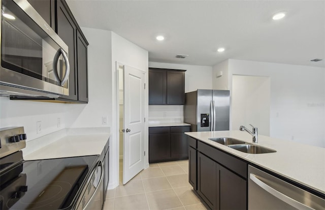 kitchen with dark brown cabinets, sink, light tile patterned floors, and stainless steel appliances