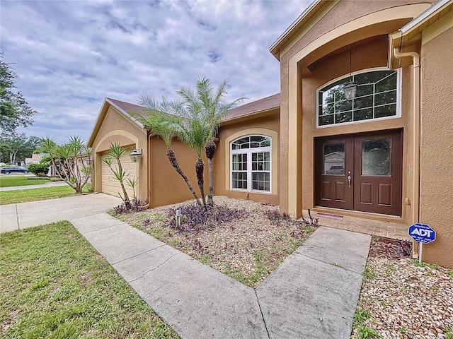 view of exterior entry with a yard and a garage