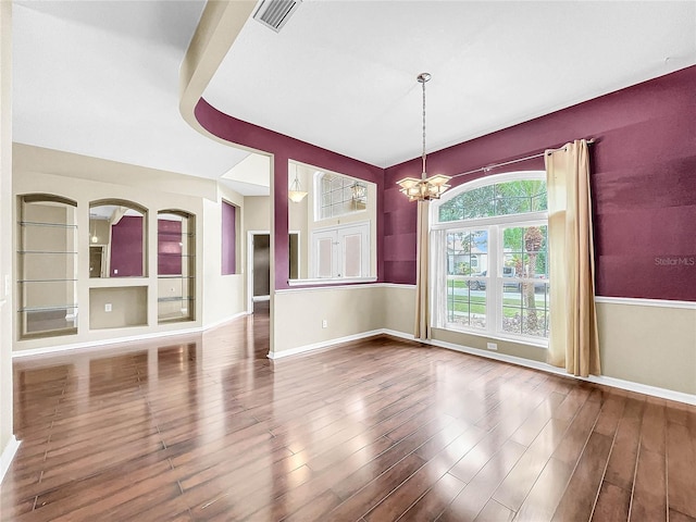 unfurnished dining area with an inviting chandelier and wood-type flooring