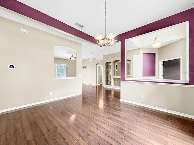 unfurnished dining area with ceiling fan with notable chandelier and hardwood / wood-style floors