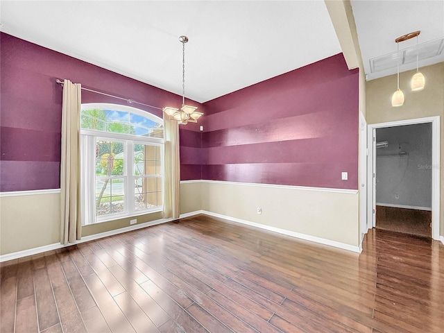 empty room with hardwood / wood-style floors and a chandelier