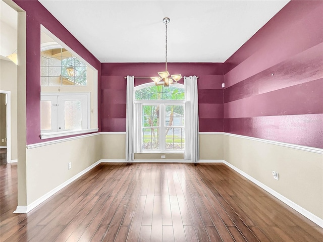 unfurnished dining area with hardwood / wood-style floors and an inviting chandelier