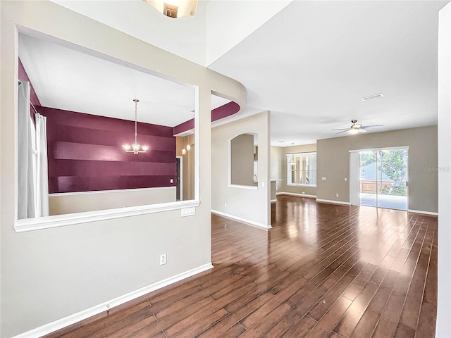 unfurnished living room featuring ceiling fan with notable chandelier and hardwood / wood-style floors