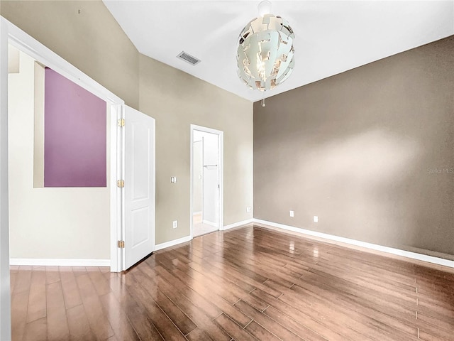 spare room featuring a notable chandelier and wood-type flooring