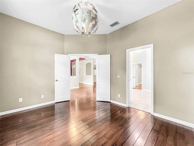 unfurnished bedroom with hardwood / wood-style flooring and a chandelier