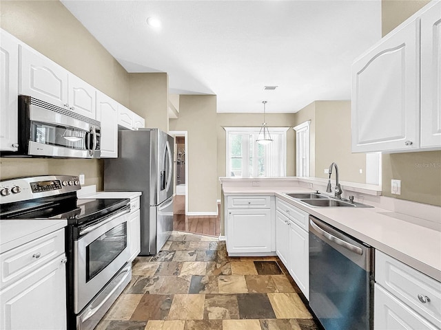 kitchen featuring light hardwood / wood-style flooring, pendant lighting, white cabinetry, sink, and stainless steel appliances