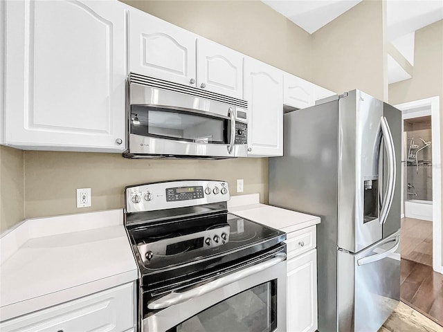 kitchen with hardwood / wood-style floors, appliances with stainless steel finishes, and white cabinetry