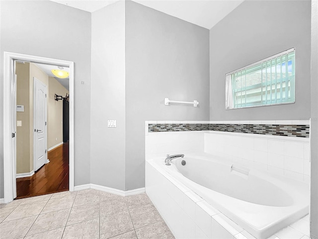 bathroom with hardwood / wood-style flooring and tiled bath