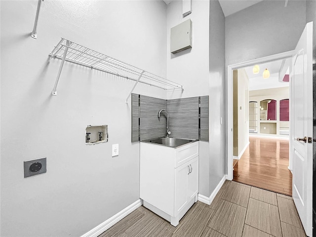 washroom with light wood-type flooring, sink, washer hookup, and hookup for an electric dryer