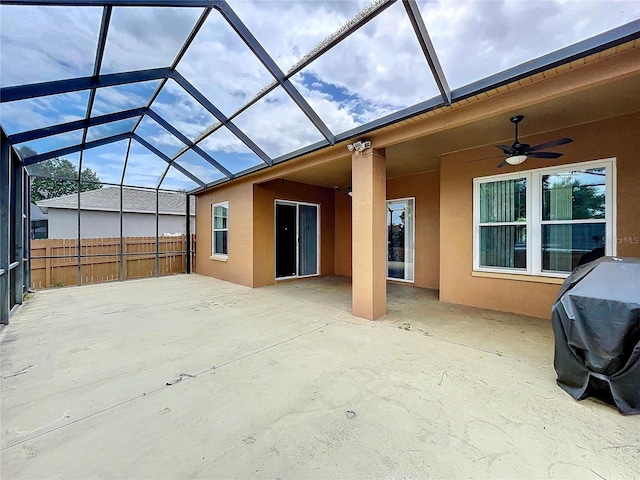 view of patio with glass enclosure, ceiling fan, and area for grilling