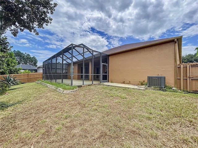 rear view of property featuring central AC unit, glass enclosure, and a lawn