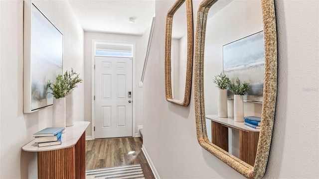 doorway to outside with a textured ceiling, wood finished floors, and baseboards