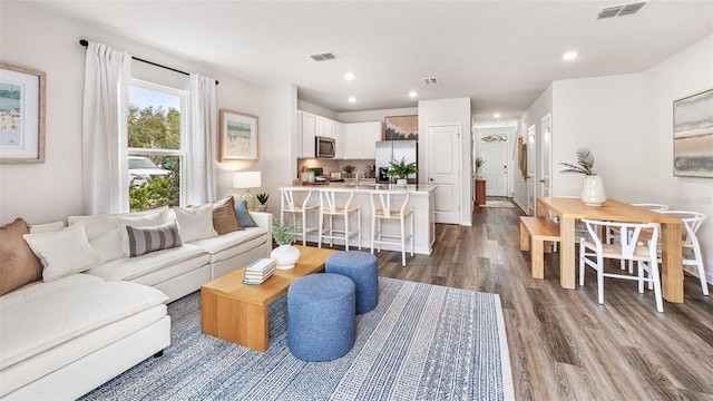 living area featuring recessed lighting, visible vents, and wood finished floors