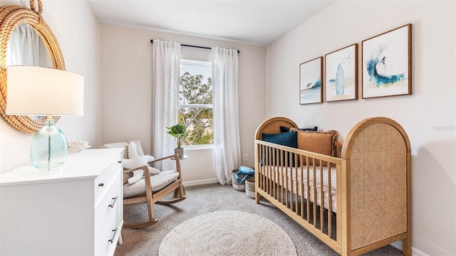 carpeted bedroom with a crib and baseboards