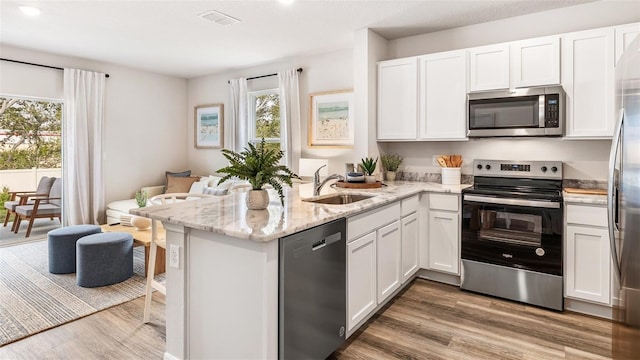 kitchen with appliances with stainless steel finishes, white cabinets, and a peninsula