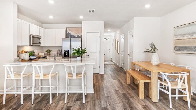 kitchen featuring stainless steel appliances, a breakfast bar, visible vents, white cabinetry, and light countertops