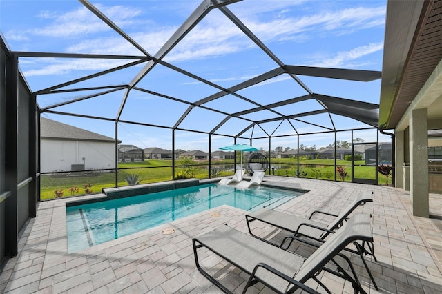 pool with glass enclosure, a patio area, a lawn, and a residential view