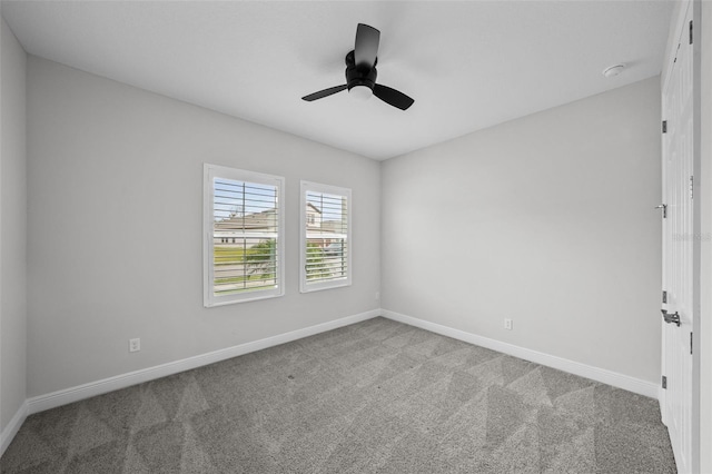 carpeted spare room featuring baseboards and ceiling fan