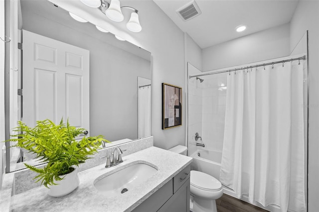 bathroom with visible vents, toilet, shower / bath combo, wood finished floors, and vanity