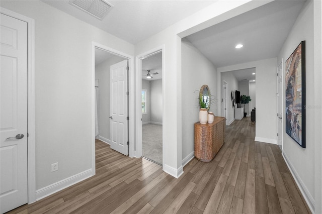 hall featuring visible vents, recessed lighting, baseboards, and wood finished floors