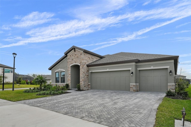 view of front facade featuring stone siding, stucco siding, decorative driveway, and a garage