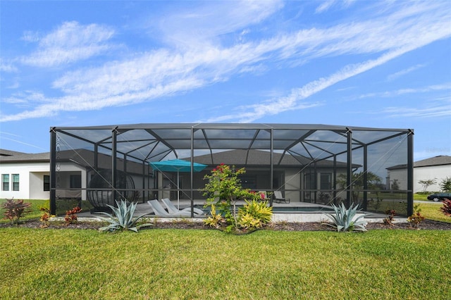 rear view of property with a lawn, an outdoor pool, glass enclosure, and stucco siding