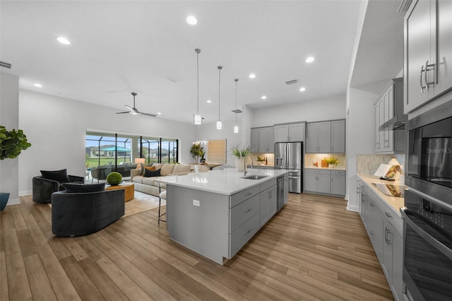 kitchen featuring a sink, stainless steel fridge, open floor plan, and gray cabinets