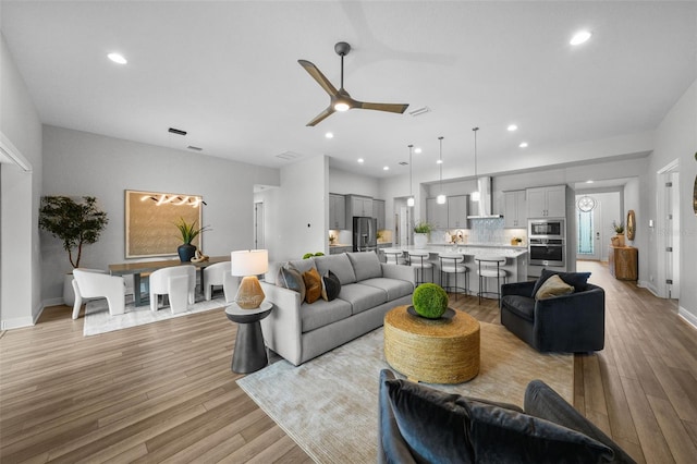 living room with light wood finished floors, recessed lighting, baseboards, and ceiling fan