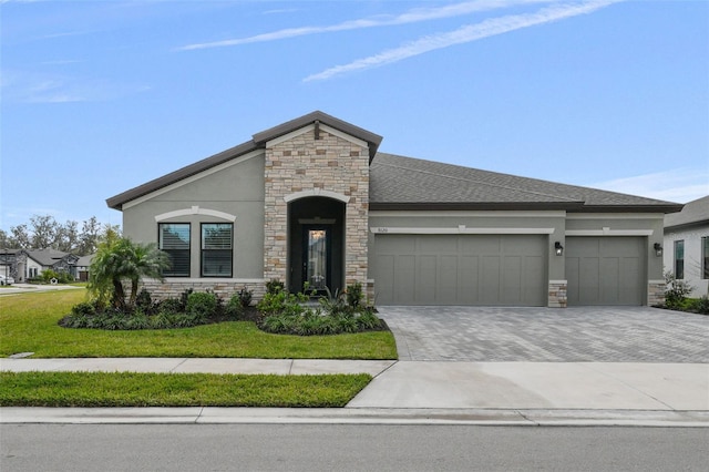 view of front facade featuring a front yard, stucco siding, decorative driveway, stone siding, and an attached garage