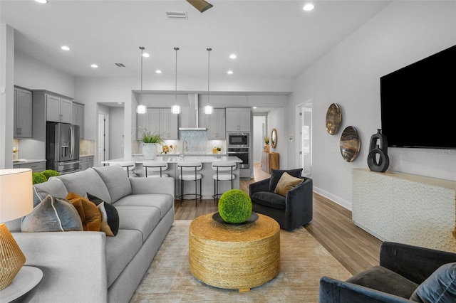 living room with light wood-style flooring, recessed lighting, visible vents, and baseboards