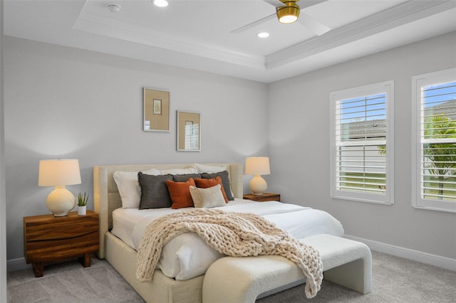 bedroom featuring a tray ceiling, multiple windows, baseboards, and light carpet