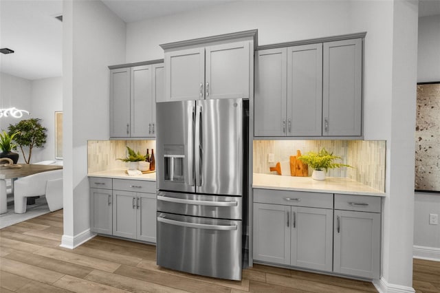 kitchen with tasteful backsplash, gray cabinets, and stainless steel fridge with ice dispenser