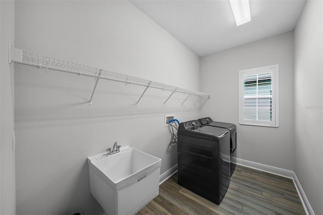 laundry area featuring a sink, baseboards, laundry area, wood finished floors, and separate washer and dryer