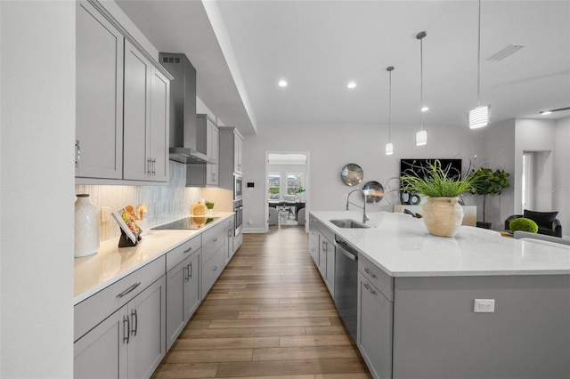 kitchen with a sink, dishwasher, gray cabinetry, and wall chimney range hood